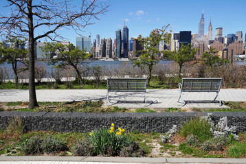 Ausblick auf die Skyline von Manhattan vom Hunters Point South Waterfront Park: Die Versickerungsmulde (Bioswale) mit Gabione in der Mitte zieht sich entlang der Ostseite des Parks und speichert Regenwasser zur Entlastung der Kanalisation bei starkem Niederschlag. 