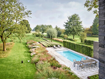 Blick ber den Garten am Stadtrand von Krefeld in die Tiefe der Landschaft: Pool, Terrasse, Staudenrabatten, Obstwiese