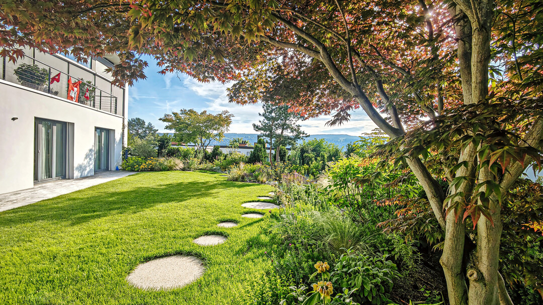 Eine lockere, organische Wegeführung mit runden Betonschrittplatten erschließt diesen Garten und führt zu einem Aussichtspunkt mit Blick auf die Alpen am Zürichsee.