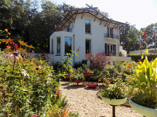 Der Gartenraum Blumen auf dem Berg mit farbigen Pflanzgefen auf Stelzen befindet sich vor der Villa.