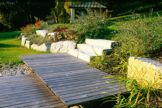 Holzsteg aus L�rchenholz auf zwei H�hen mit Blockstufen aus Granit im Anschluss