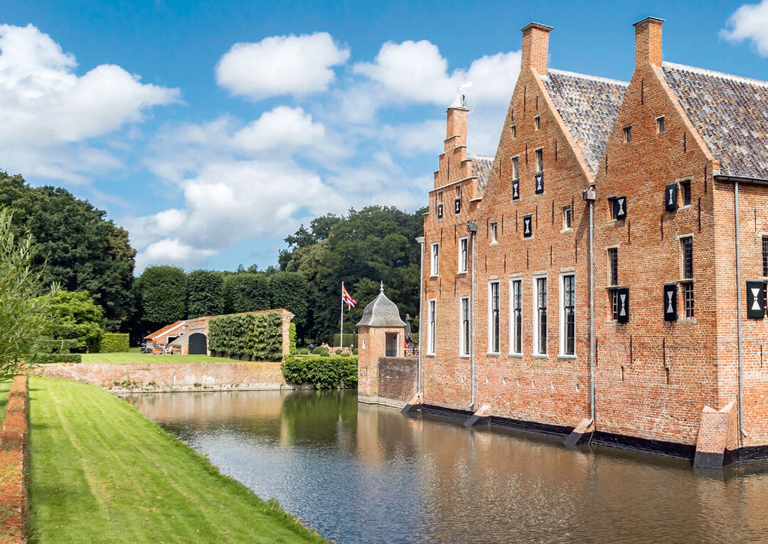 Die Wasserburg Menkemaborg ist von einem inneren Wassergraben umgeben, der zweite äußere Wassergraben verläuft entlang der Gartengrenze. Im Hintergrund die Kastenlinden und der Rotbuchenwald.