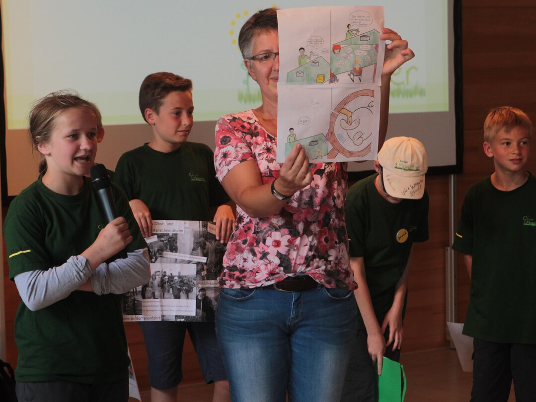 Minigrtnerin Ccilie Keck (links auen) und ihre Minigrtner-Kollegen aus Ellwangen berichten von ihren Erlebnissen in Gartenbau-Betrieben in und um Ellwangen. Die selbst gestalteten Plakate zeigt Christiane Karger (Mitte) von der Obst- und Gartenbauberatung des Landratsamtes Ostalb ins Publikum. Christiane Karger ist die Teamleiterin der Minigrtner Ellwangen.